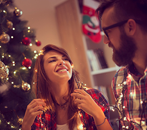 Couple decorates the Christmas tree with lights